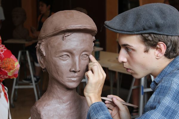 High School student sculpting clay head self portrait