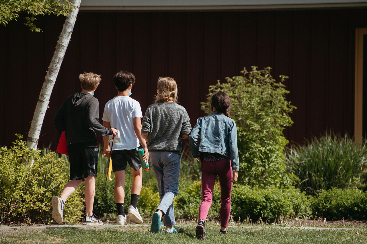 Four Middle School students walking side by side near the school