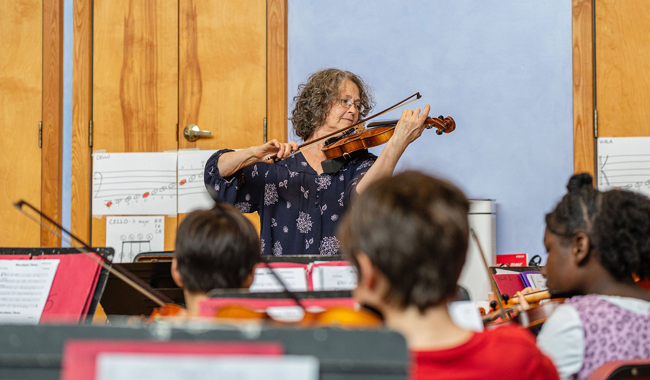 Strings Music Teacher Alison Eldredge demonstrates violin during fifth grade strings class