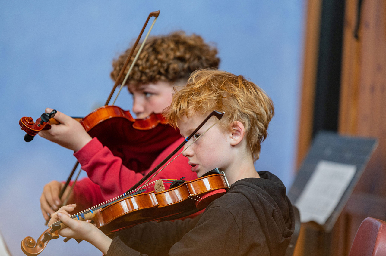 Two fifth grade boys playing violins during strings class