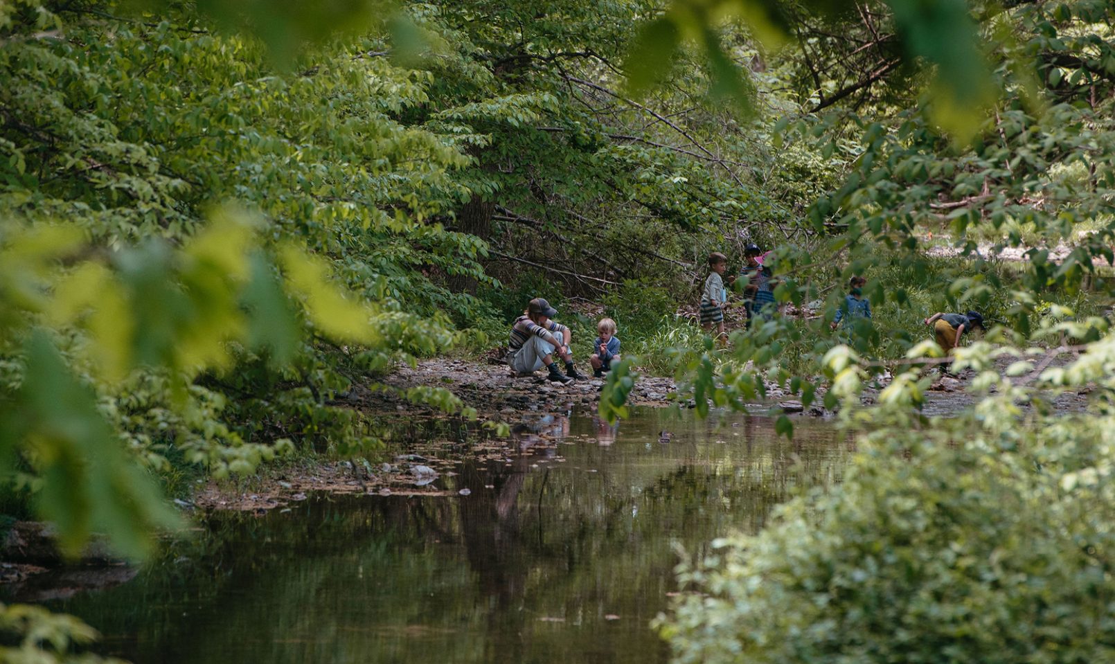 The beautiful crystal clear Agawamuck Creek runs behind the school. In this photo there is a group of small children and adults exploring the creek in the distance