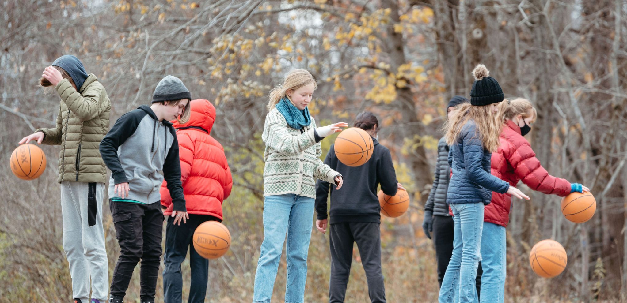 group of students dribbling basketballs outdoors in the winter