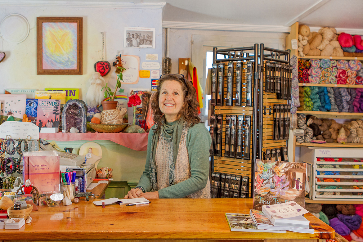 Interior of Turose Gift Shoppe and School Store; Caroline O'Neill, the shop proprietor stands at the checkout counter smiling while looking into the camera