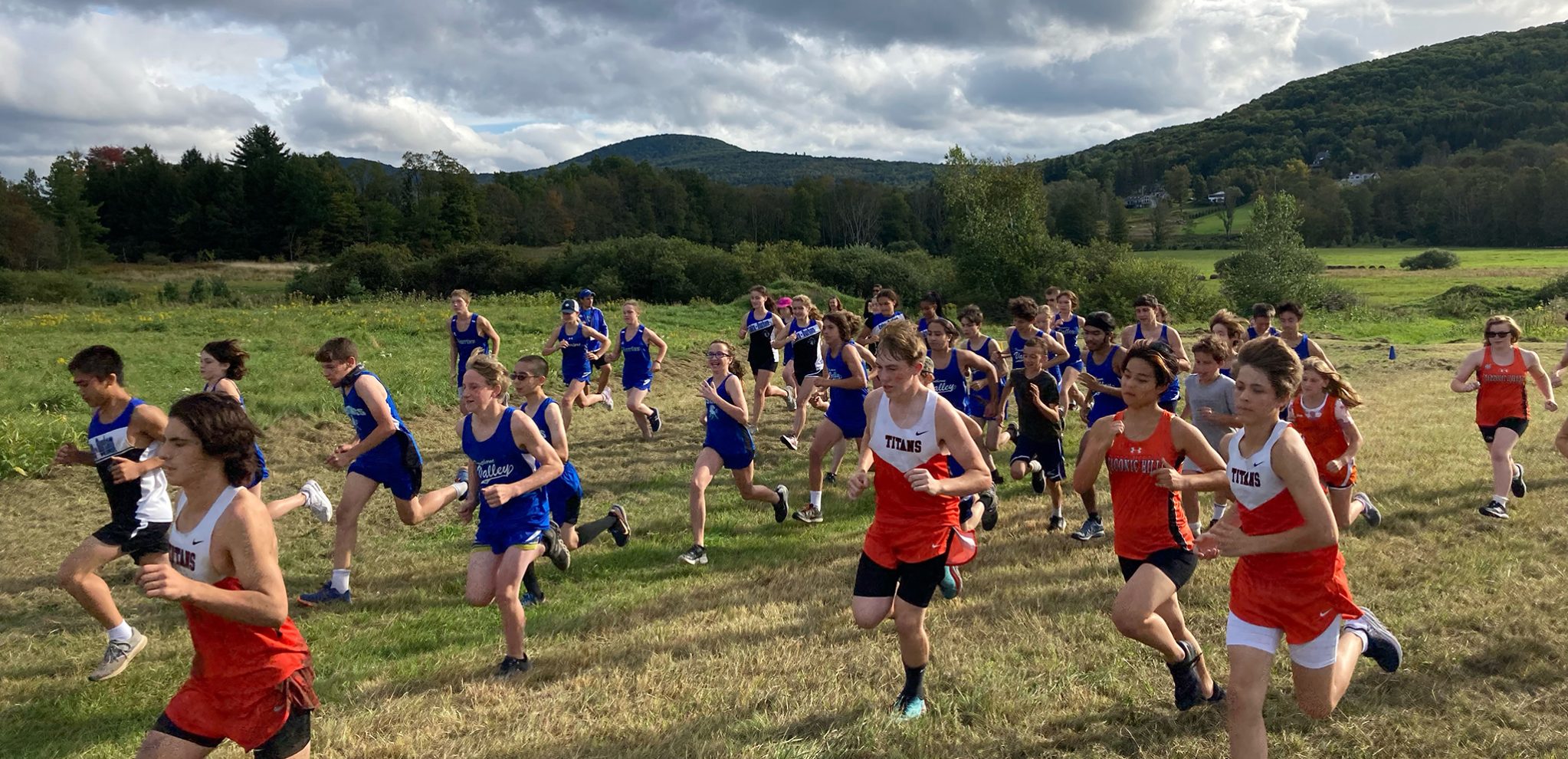 Cross country runners at the start of a race; there are mountains in the background